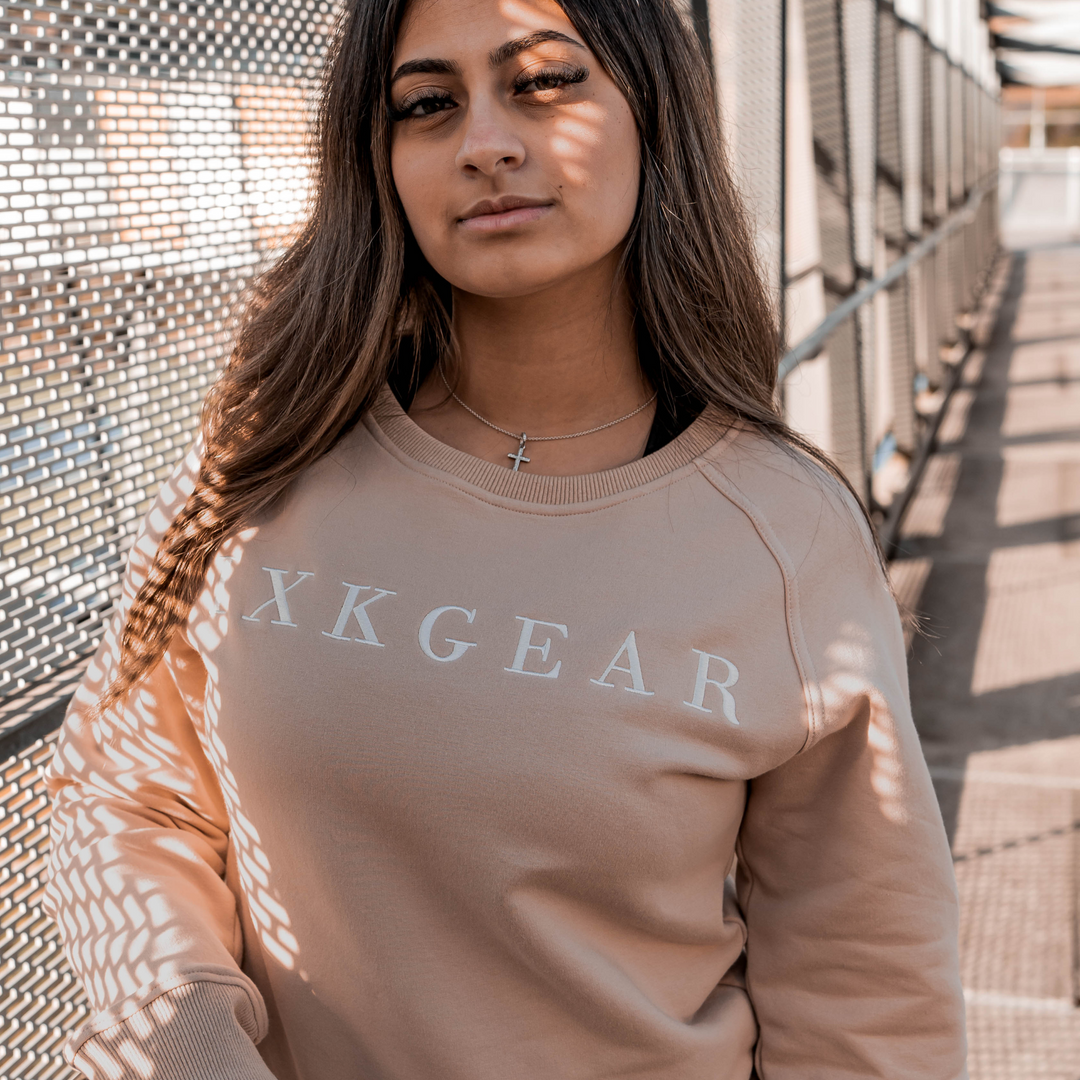IXK Gear Crewneck Jumper in colour: Sand. Metal grate background and shadow on model face.